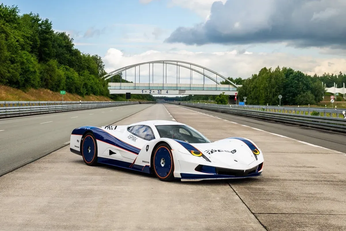 Aspark Owl Un auto de carrera eléctrico de diseño aerodinámico, pintado principalmente de blanco con detalles azules y amarillos.