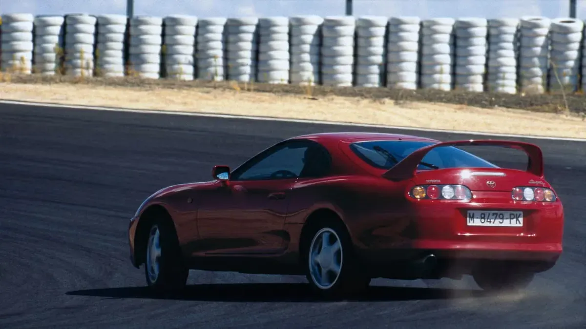 Toyota Supra Un auto deportivo rojo avanzando en una curva sobre pista.