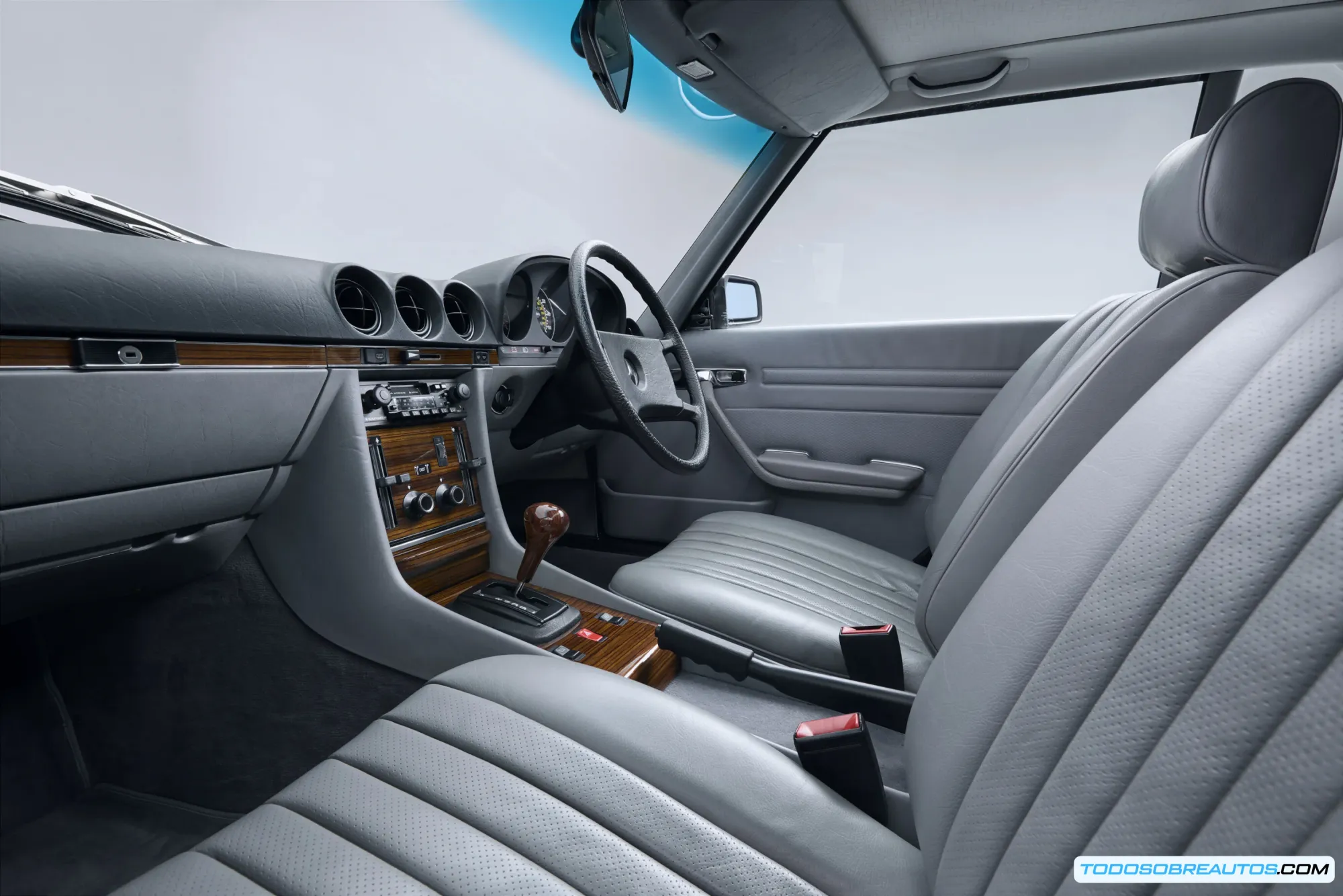 Mercedes Benz SL R107 de 1983 color azul verdoso metalizado en vista lateral, mostrando su diseño atemporal y la capota cerrada.