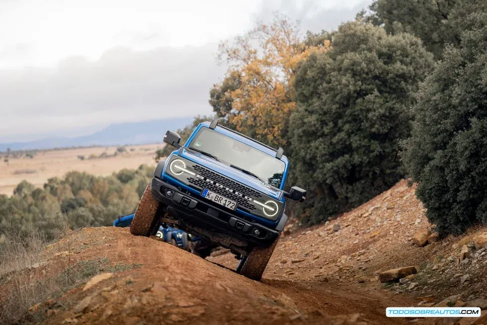 Vista frontal de un Ford Bronco cruzando con seguridad un tramo de agua poco profunda, demostrando una técnica de conducción todoterreno aprendida en el programa.