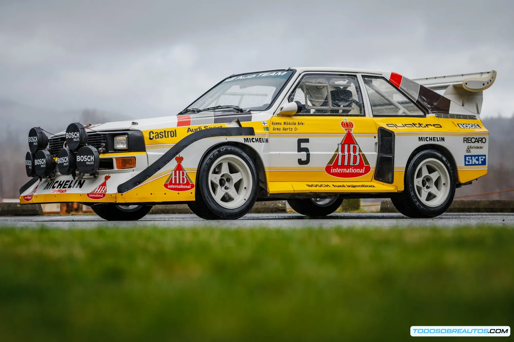 Audi Sport Quattro compitiendo en rally mostrando su agresiva carrocería y alerón trasero en plena acción sobre tierra