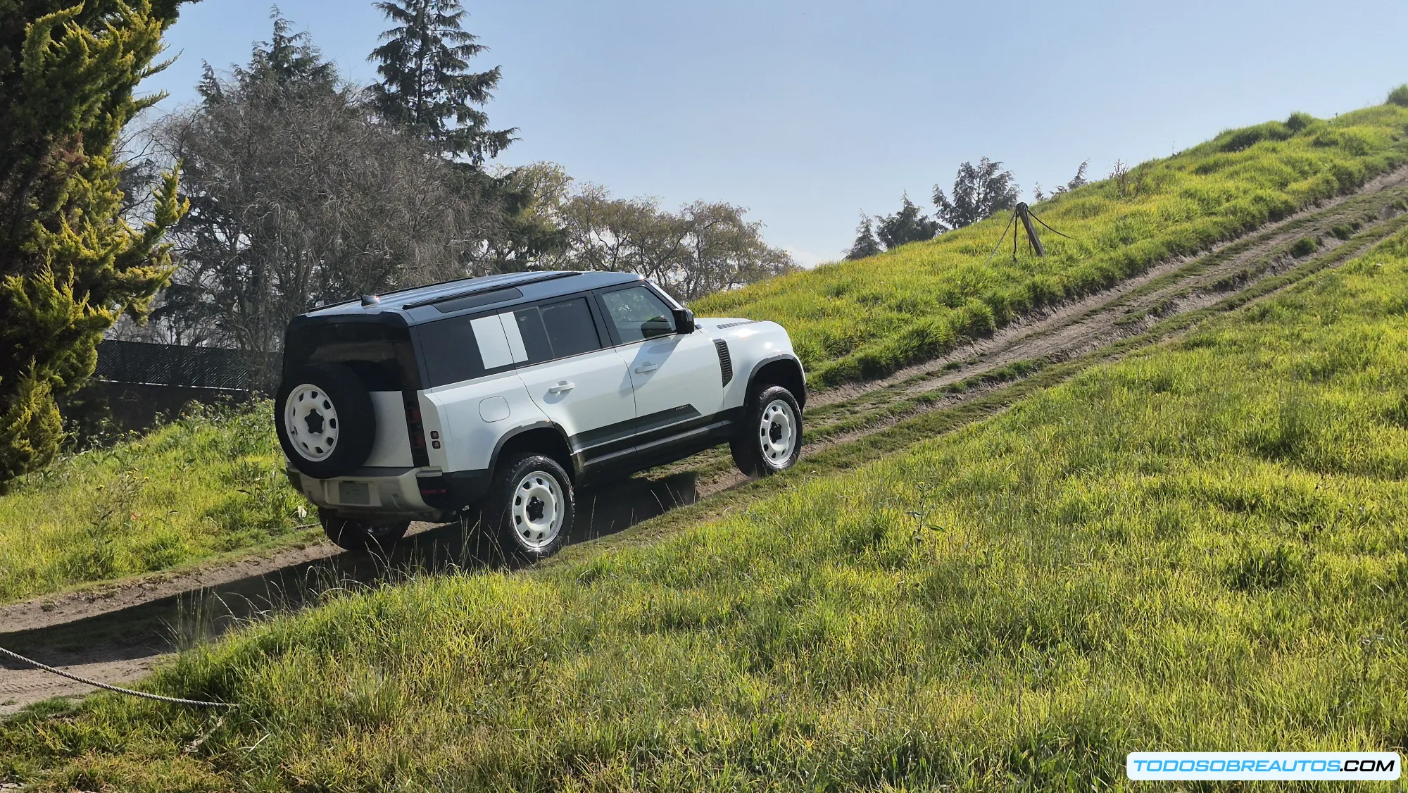 Land Rover Defender 2024 superando obstáculos off-road, mostrando sus capacidades todoterreno y diseño icónico con rines de aleación y llantas todo terreno