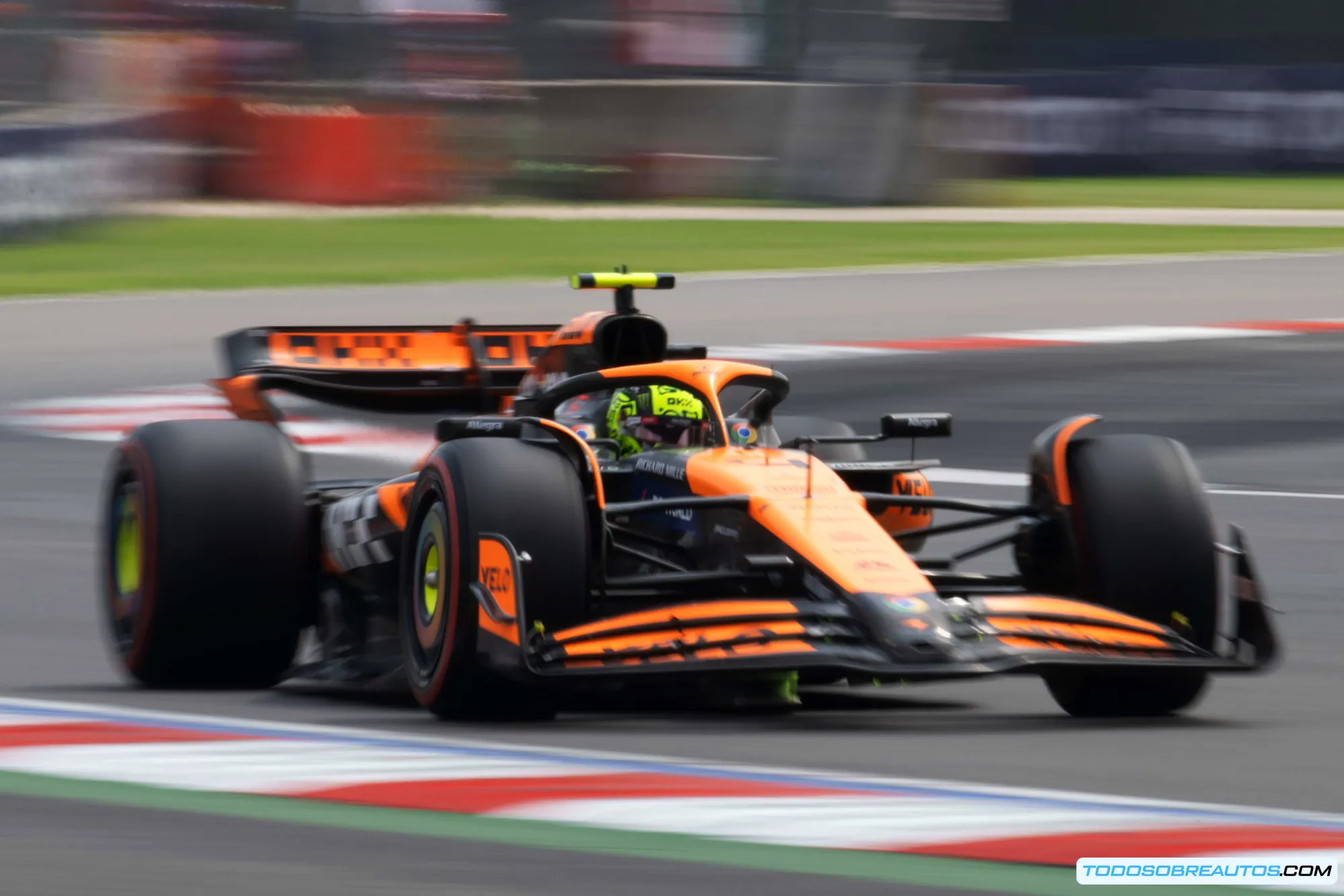 El monoplaza McLaren MCL38 de Fórmula 1 en acción en una recta, mostrando su diseño aerodinámico, alerones y librea naranja y azul característica del equipo.