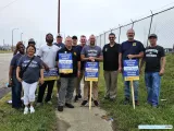 Trabajadores de Teamsters en piquete, con un cartel mostrando su descontento.