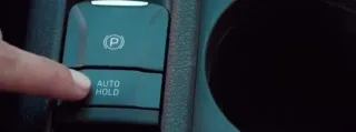 Dedo presionando boton de Auto Hold de un auto