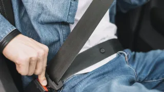 Mano presionando cinturon de segurirdad