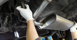 Manos sosteniendo sistema de escape de un auto
