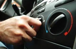Mano girando botón de aire acondicionado en auto