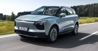 Un SUV gris moderno circulando en una carretera rodeada de naturaleza.