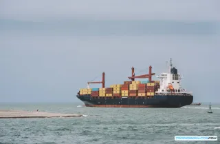 Buque portacontenedores navegando en aguas árticas con hielo visible, simbolizando la nueva ruta marítima para el comercio de coches eléctricos chinos.