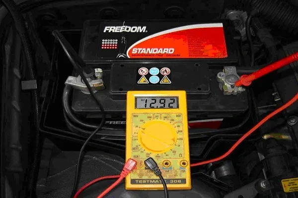 Un voltímetro tomando el voltaje de una bateria de auto