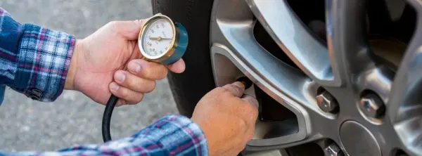 Manos utilizando un medidor de aire en un neumático