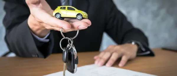 Manos entregando auto de juguete amarillo y llaves de auto 